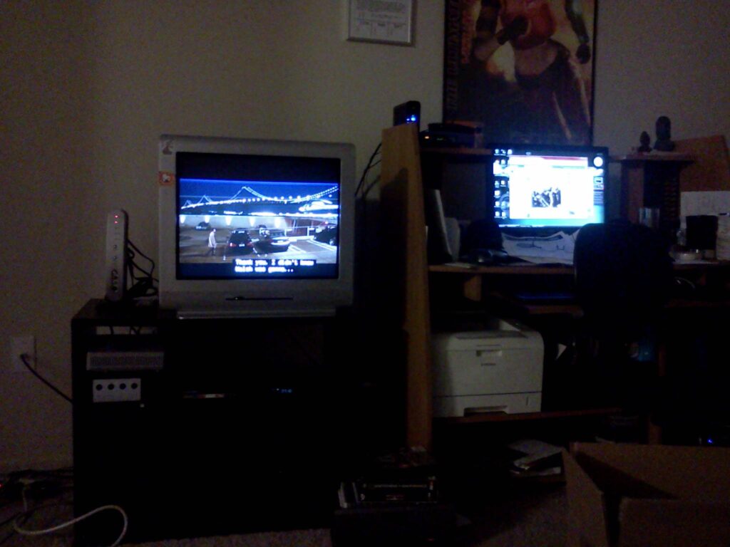 A poorly lit photo of a living room entertainment center and a computer desk.